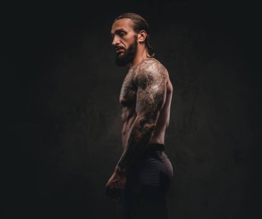 Spor giyim bir sakallı dövmeli sporcu profili. Karanlık dokulu arka plan üzerinde izole.