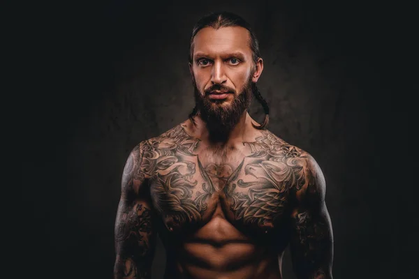 Portrait of a shirtless bearded tattooed male. Isolated on dark textured background. — Stock Photo, Image