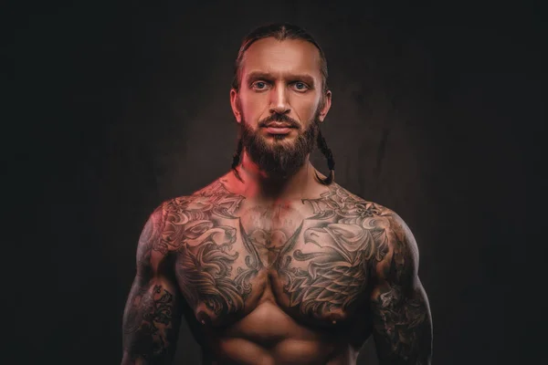 Close-up photo of a brutal shirtless bearded tattooed male. Isolated on a dark textured background. — Stock Photo, Image