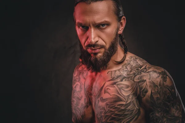 Närbild av en brutal shirtless skäggig tatuerade hane. Isolerad på en mörk texturerat bakgrund. — Stockfoto