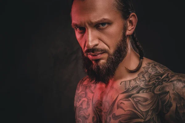 Close-up photo of a brutal shirtless bearded tattooed male. Isolated on a dark textured background. — Stock Photo, Image