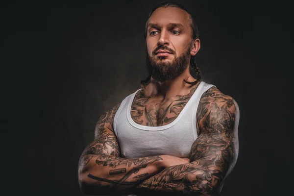 Brutal bearded tattooed male in white shirt posing with crossed arms.  Isolated on a dark textured background. - Stock Image - Everypixel