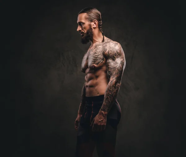 Perfil de um atleta tatuado barbudo em sportswear. Isolado em fundo escuro texturizado . — Fotografia de Stock