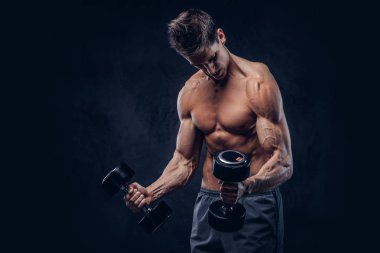 Yakışıklı gömleksiz adam şık saç ve kas ectomorph vücut egzersizleri dumbbells ile yapıyor.