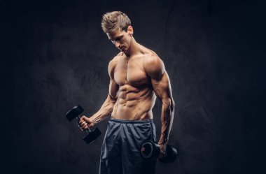 Yakışıklı gömleksiz adam şık saç ve kas ectomorph vücut egzersizleri dumbbells ile yapıyor.