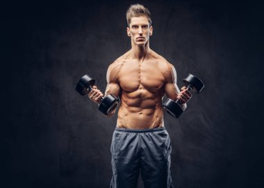 Yakışıklı gömleksiz adam şık saç ve kas ectomorph vücut egzersizleri dumbbells ile yapıyor.