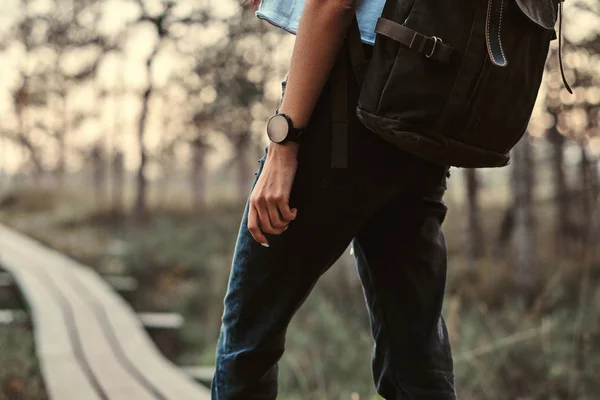 Foto recortada de una chica turística con mochila a pie en un sendero de madera en el hermoso bosque . — Foto de Stock