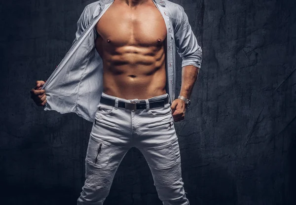 Cropped photo of a sporty man with a muscular body in unbutton shirt and jeans posing in studio. — Stock Photo, Image