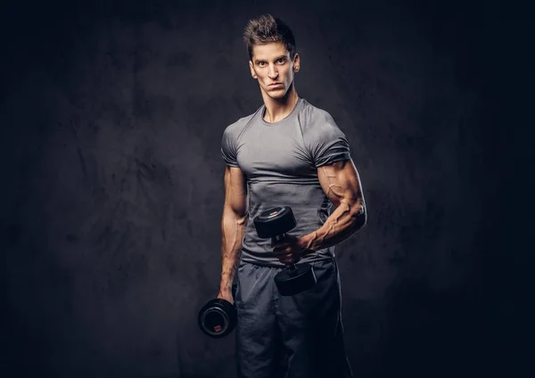 Esportista bonito com cabelo elegante vestido em um sportswear fazendo os exercícios com halteres . — Fotografia de Stock