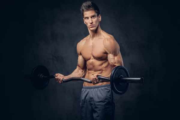 Bonito homem sem camisa com cabelo elegante e ectomorfo muscular fazendo os exercícios com a barra . — Fotografia de Stock