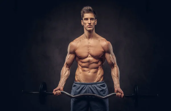 Bonito homem sem camisa com cabelo elegante e ectomorfo muscular fazendo os exercícios com a barra . — Fotografia de Stock