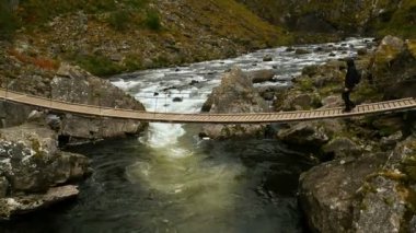 Turistik Norveç'te bir dağ dere üzerinde ahşap köprü yürür.