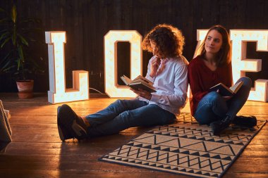 Bir yere oturmak ve aydınlatma ile hacimli harfleri ile dekore edilmiş bir odada birlikte okuma genç öğrenci çift.