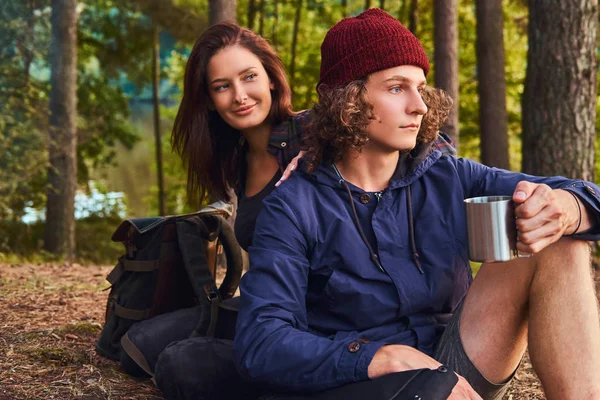 Egy fiatal pár - szép göndör srác, és ül össze, az erdő, a bájos lány portréja. — Stock Fotó