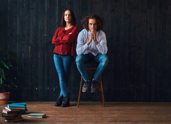 Pareja de jóvenes estudiantes con libros en una habitación con el interior minimalista . — Foto de Stock