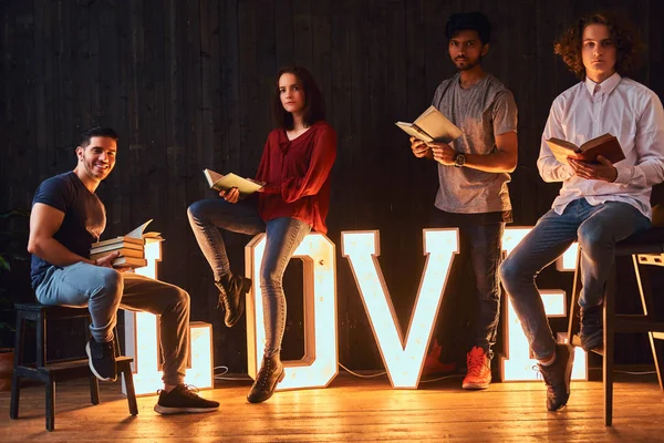 L'amour de l'éducation. Groupe international d'étudiants avec des livres dans la salle décorée de lettres volumineuses avec éclairage . — Photo