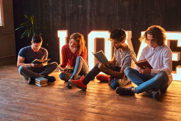 Internationell grupp studenter läsa böcker i ett rum inredda med voluminösa bokstäver med belysning. — Stockfoto