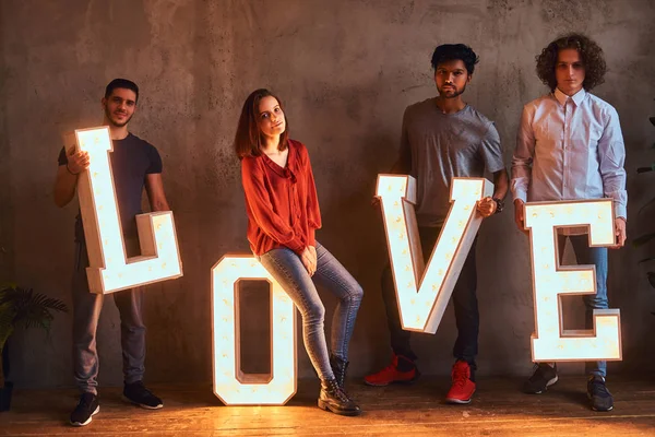 Grupo internacional de estudiantes posando con letras voluminosas con iluminación . —  Fotos de Stock