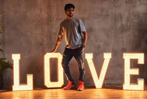 Joven indio de moda posando con letras voluminosas con iluminación . — Foto de Stock