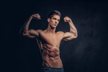 Yakışıklı gömleksiz adam şık saç ve kas ectomorph onun pazı gösterir.