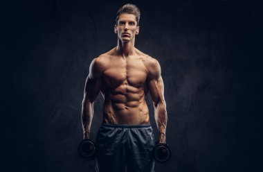 Yakışıklı gömleksiz adam şık saç ve kas ectomorph vücut egzersizleri dumbbells ile yapıyor.