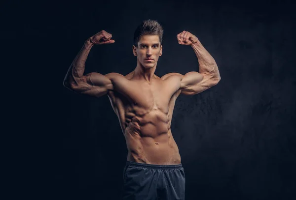 Bonito homem sem camisa com cabelo elegante e ectomorfo muscular mostra seu bíceps . — Fotografia de Stock