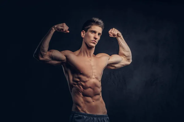 Bonito homem sem camisa com cabelo elegante e ectomorfo muscular mostra seu bíceps . — Fotografia de Stock