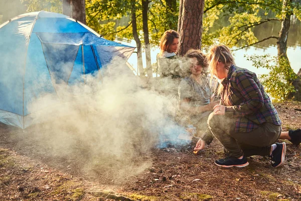 Drei Freunde wandern im Wald und versuchen, im Lager ein Feuer zu entzünden. — Stockfoto