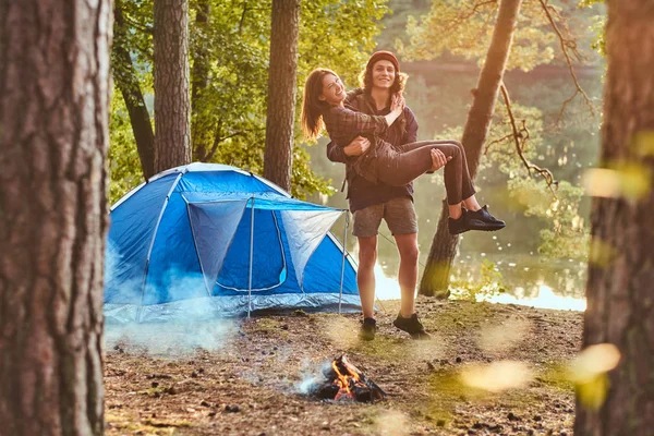 Lyckligt par av vandrare ha kul nära en lägereld på camp i skogen. — Stockfoto