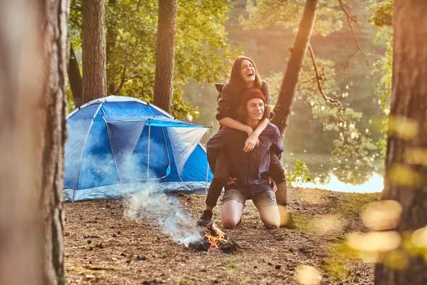 Coppia felice di escursionisti che si divertono vicino a un falò al campo nella foresta . — Foto Stock