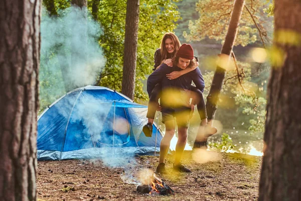 Boldog pár túrázók érzik magukat közelében egy tábortűz a tábor az erdő. — Stock Fotó