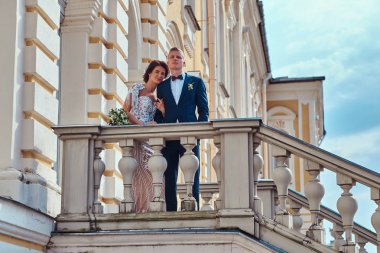 Güneşli bir günde güzel eski sarayın merdivenlerde dururken sarılma güzel yeni evliler.