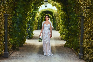 Bir bahçede düğün buket tutan inanılmaz elbise muhteşem mutlu gelin.