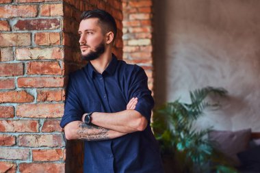 Dalgın sakallı adam çatı iç ofiste masaüstü yakınındaki çapraz kolları olan ayakta.