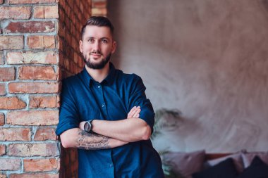 Sakallı adam masaüstü ofis çatı iç yakınındaki çapraz silah ile ayakta gülümseyen.