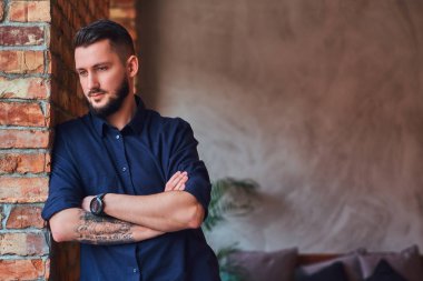 Dalgın sakallı adam çatı iç ofiste masaüstü yakınındaki çapraz kolları olan ayakta.