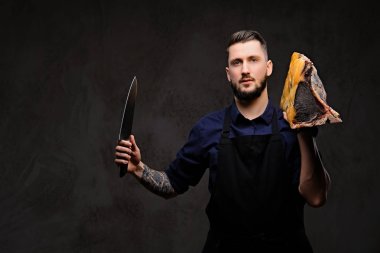 Şef aşçı bıçak ve büyük özel tedavi et parçası karanlık bir arka plan üzerinde tutar.