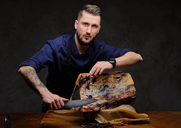 Кухар готує різання ексклюзивного м'яса на столі в мисливському будинку на темному фоні . — стокове фото