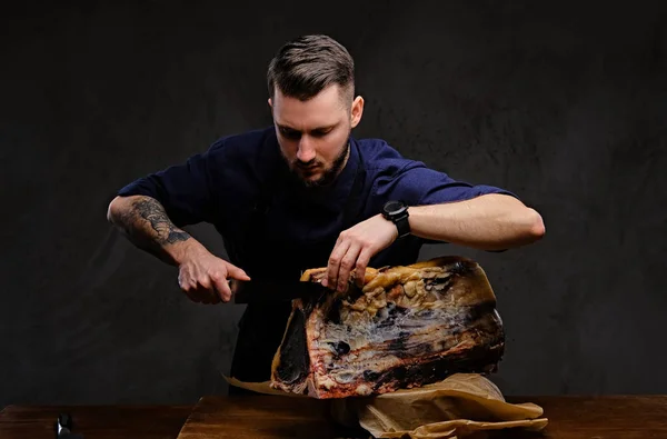 Фокусований шеф-кухар готує різання ексклюзивного м'яса на столі в мисливському будинку на темному фоні . — стокове фото