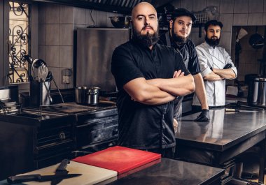 Takım profesyonel sakallı aşçıların mutfakta ayakta üniforma giymiş.