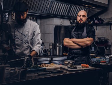 İki acımasız aşçılar bir mutfak suşi hazırlama üniforma giymiş.