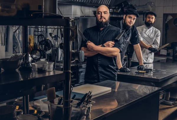Takım profesyonel sakallı aşçıların mutfak bıçak ile poz üniforma giymiş. — Stok fotoğraf