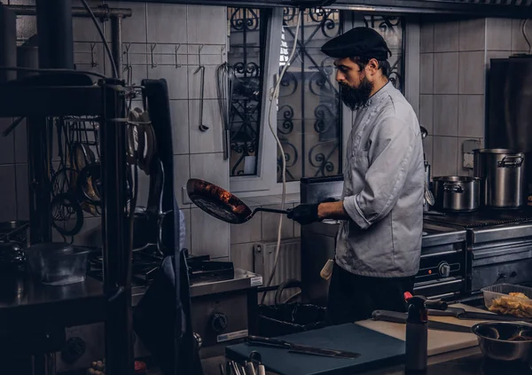 Bebaarde cook gekleed in uniform en hoed voorbereiding sushi in keuken. — Stockfoto