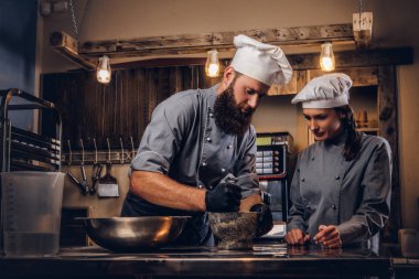 Şef susam tohumu ekmek yemek pişirmek için bir harç içinde biler. Şef Yardımcısı fırın ekmek pişirmeye öğretim.