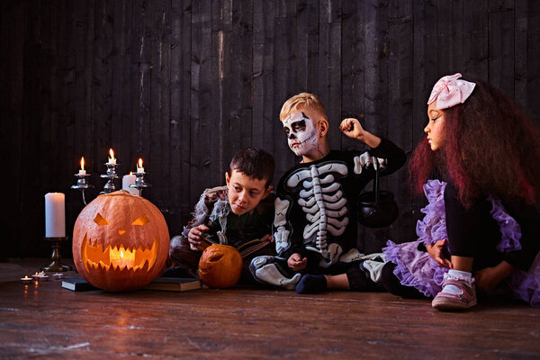 Группа милых многорасовых детей в страшных костюмах во время Хэллоуинской вечеринки в старом доме
.