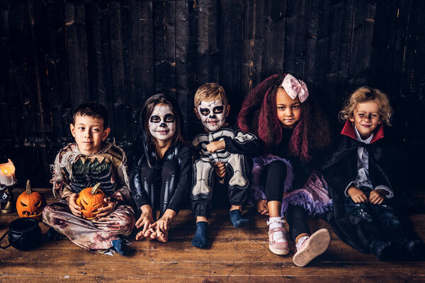 Вечеринка на Хэллоуин с группой детей, которые сидят вместе на деревянном полу в старом доме. Концепция Хэллоуина
.