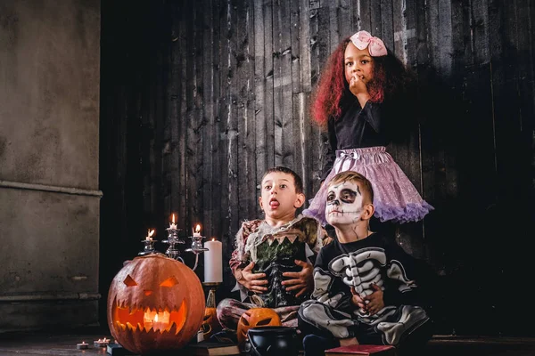 Grupo de crianças multirraciais bonitos em trajes assustadores durante a festa de Halloween em uma casa velha . — Fotografia de Stock