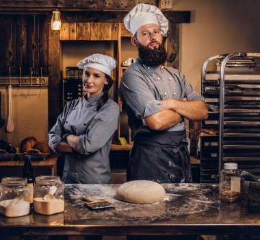 Şef asistanı aşçı üniformalı hazır hamur ekmek içinde tabloyla yakınındaki çapraz silah ile poz ile.