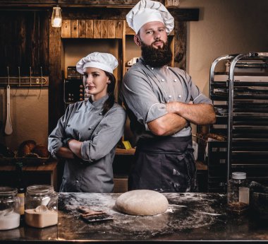 Şef asistanı aşçı üniformalı hazır hamur ekmek içinde tabloyla yakınındaki çapraz silah ile poz ile.