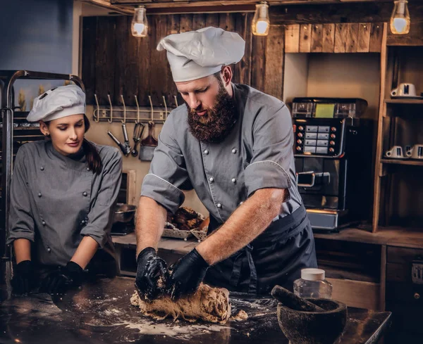 Chef amasando masa en la cocina. Chef enseñando a su asistente a hornear el pan en la panadería . —  Fotos de Stock